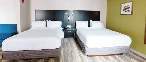 A hotel room with two beds, a nightstand, a lamp, and a framed picture on the wall.