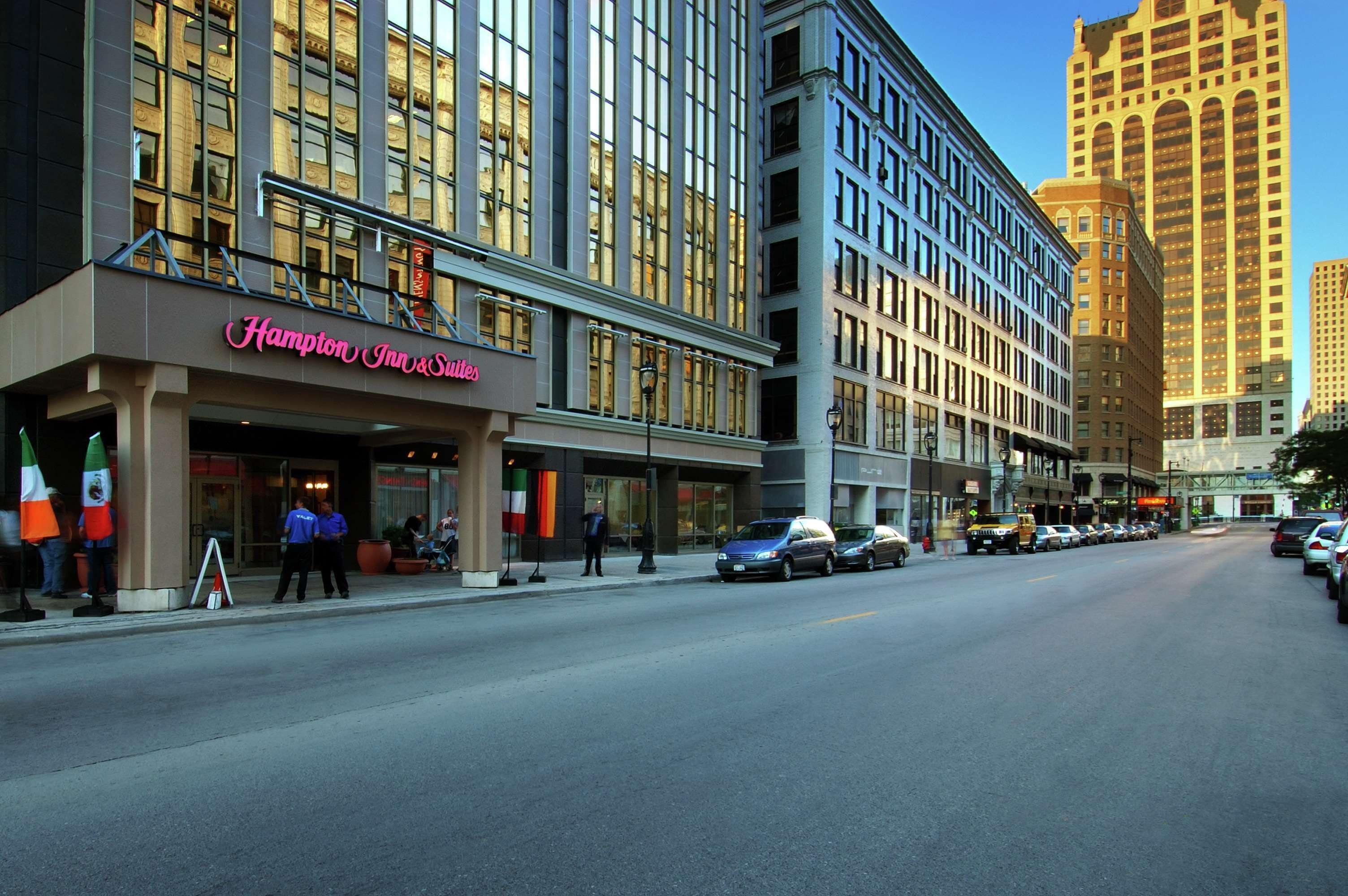 A hotel with a prominent sign reading "Hampton Inn & Suites" on the ground floor.