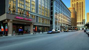 A hotel with a prominent sign reading "Hampton Inn & Suites" on the ground floor.