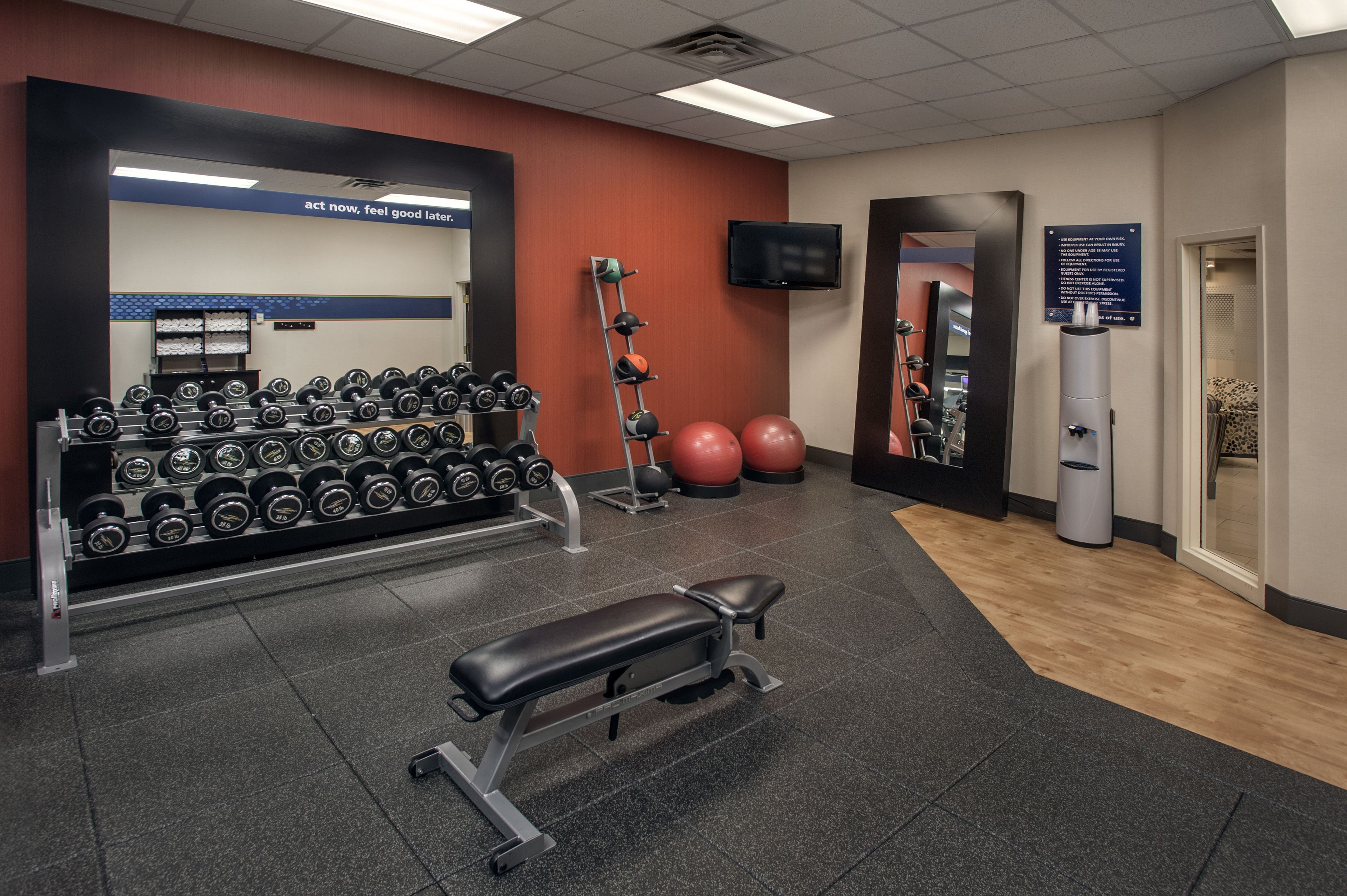 A gym with weightlifting equipment, a bench, and exercise balls.