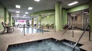 Un espace piscine d’une profondeur de 3 pieds 9 pouces, entouré de chaises et de tables, et une cloison en verre en arrière-plan.