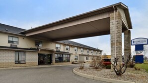 A Lexington Inn & Suites with a covered walkway, multiple windows, and a parking area. - Lexington Inn & Suites Windsor (Windsor)