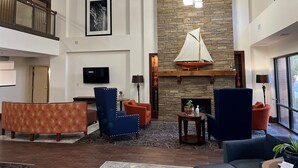 A spacious lobby with a high ceiling, a stone fireplace, a mounted sailboat, and a flat-screen TV. - Hamilton Inn Bessemer, AL - Birmingham (Bessemer)