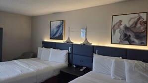 A hotel room with two beds, a nightstand, a lamp, and artwork on the walls. - Hamilton Inn Bessemer, AL - Birmingham (Bessemer)