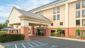 A hotel entrance with a covered area, a parking lot with handicapped spaces, and a clear sky. - Hamilton Inn Bessemer, AL - Birmingham (Bessemer)