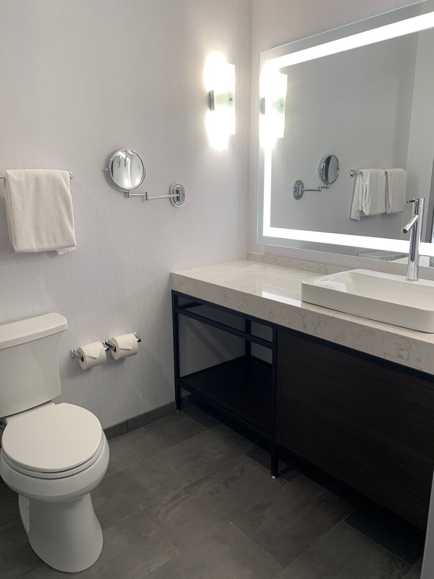 Un baño moderno con inodoro, lavabo y espejo grande.