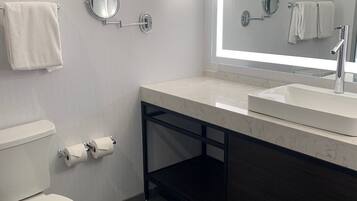 Un baño moderno con inodoro, lavabo y espejo grande.