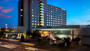 A multi-story hotel with a modern design, featuring a prominent entrance with glass doors and a flag display. - Hyatt Regency Pittsburgh International Airport (Pittsburgh)
