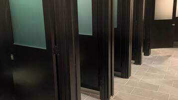 A hallway with multiple dark-colored doors, each with a frosted glass panel. The floor is tiled with large, light-colored tiles.
