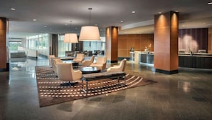 A modern lobby with a reception desk, seating area, and a staircase leading to upper floors. - Hyatt Regency Pittsburgh International Airport (Pittsburgh)