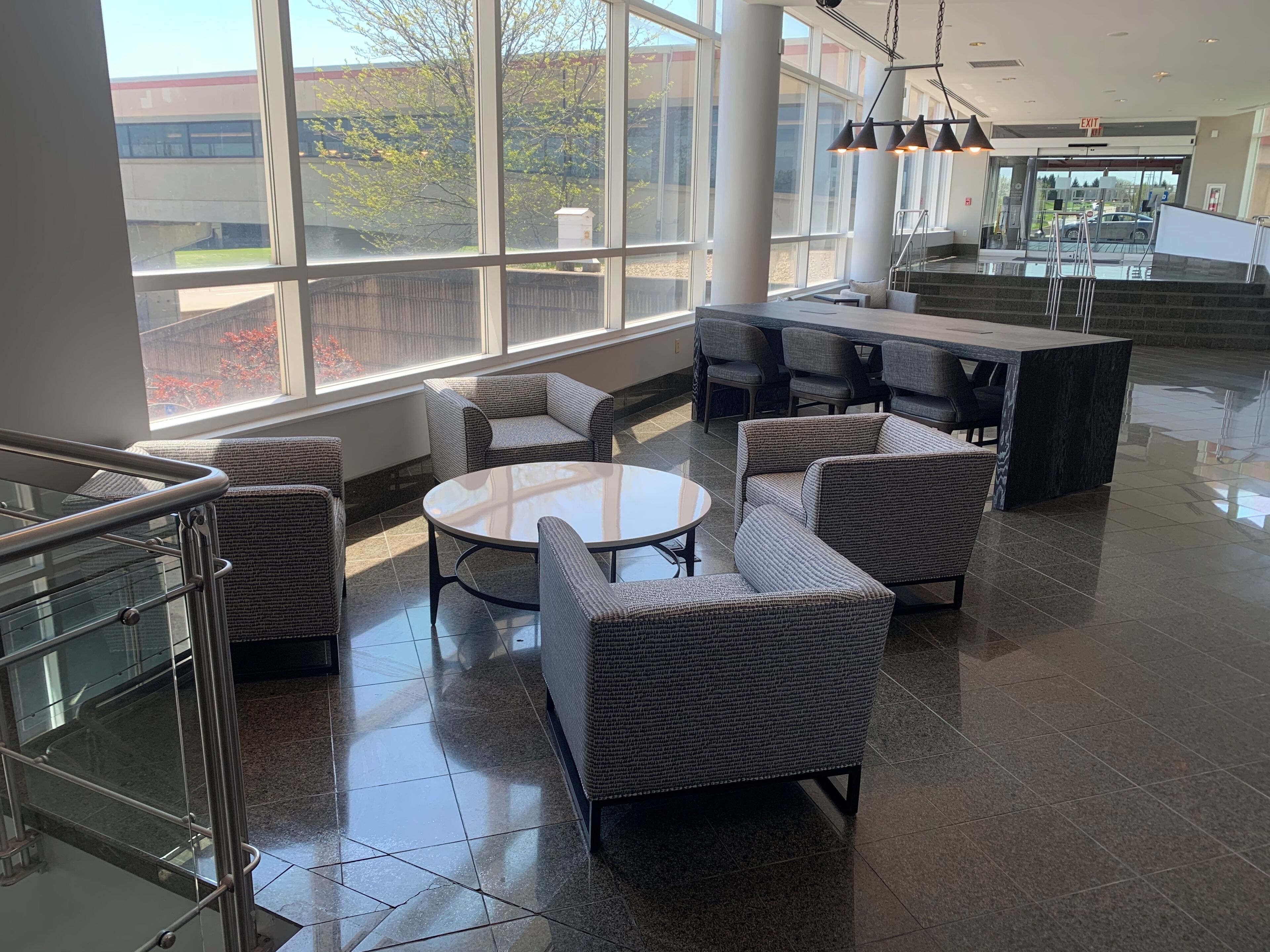 A spacious lobby with a seating area featuring wicker furniture and a glass-top table.
