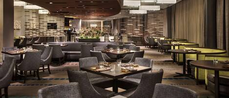 Un restaurante moderno con varias zonas de comedor, incluyendo un bar y una sala privada.