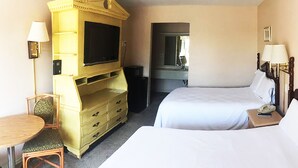 A hotel room with a bed, a desk with a chair, a television, and a dresser.