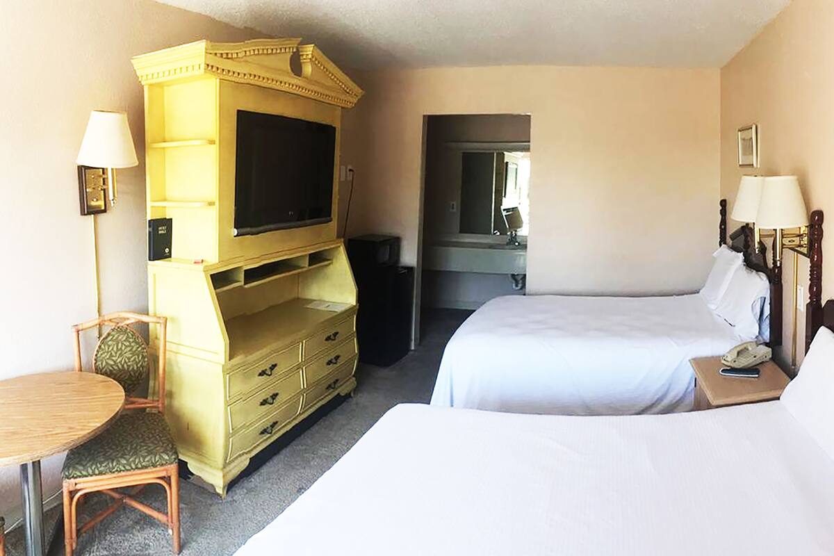 A hotel room with a bed, a desk with a chair, a television, and a dresser.