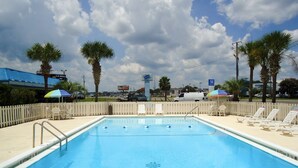 Una piscina con lettini e palme.