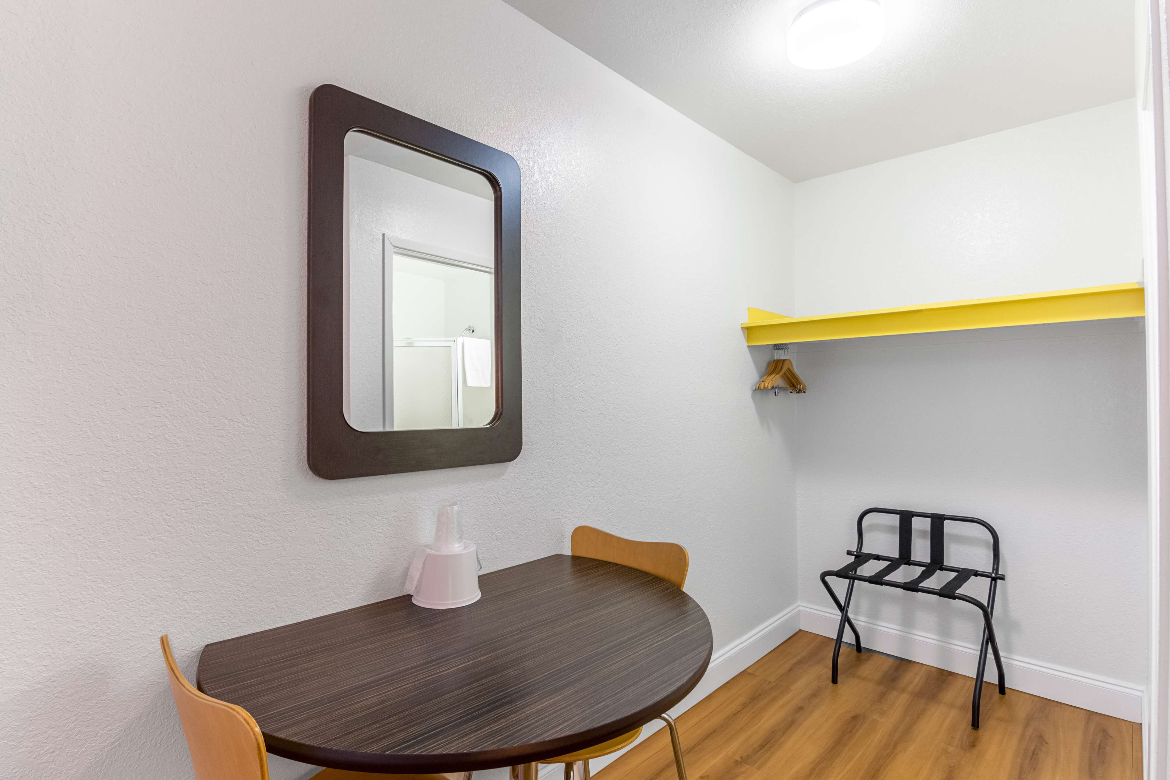 A small dining area with a round table, two chairs, a mirror, and a black metal chair.