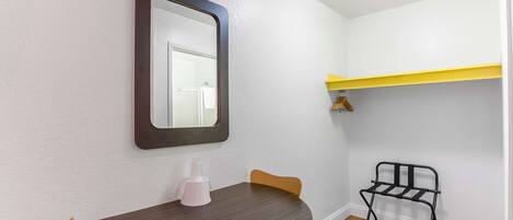 Un pequeño comedor con una mesa redonda, dos sillas, un espejo y una silla de metal negro.