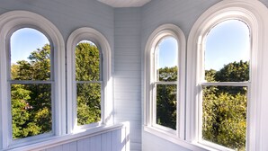 Una habitación con tres ventanas arqueadas y techo inclinado.