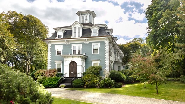 Una casa grande e histórica con una entrada principal destacada, múltiples ventanas y un jardín bien cuidado.