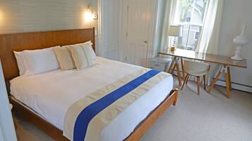 A hotel room with a large bed, a desk, and a chair.