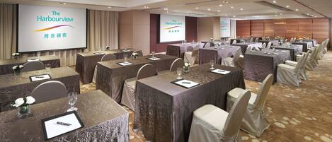 A conference room with multiple tables set for a meeting, equipped with nameplates, pens, and glasses.