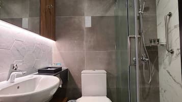 A modern bathroom with a glass shower enclosure, a white toilet, and a vanity with a sink.