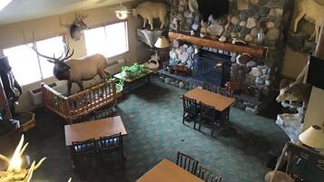 A cozy interior with a stone fireplace, wooden furniture, and mounted animal heads.