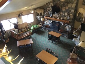 A cozy interior with a stone fireplace, wooden furniture, and mounted animal heads. - AmericInn by Wyndham Cody (Cody)