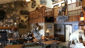 A restaurant with wooden furniture, stone walls, and mounted animal heads. - AmericInn by Wyndham Cody (Cody)