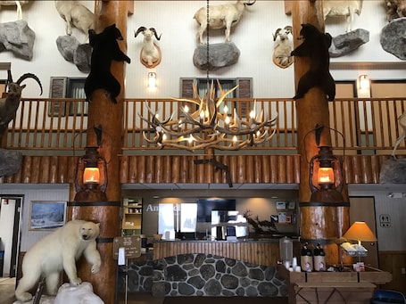 A lobby with a stone wall, wooden paneling, a chandelier, and various animal taxidermy.