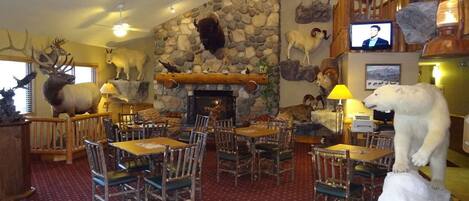 A restaurant with a stone wall, wooden furniture, and various animal taxidermy.