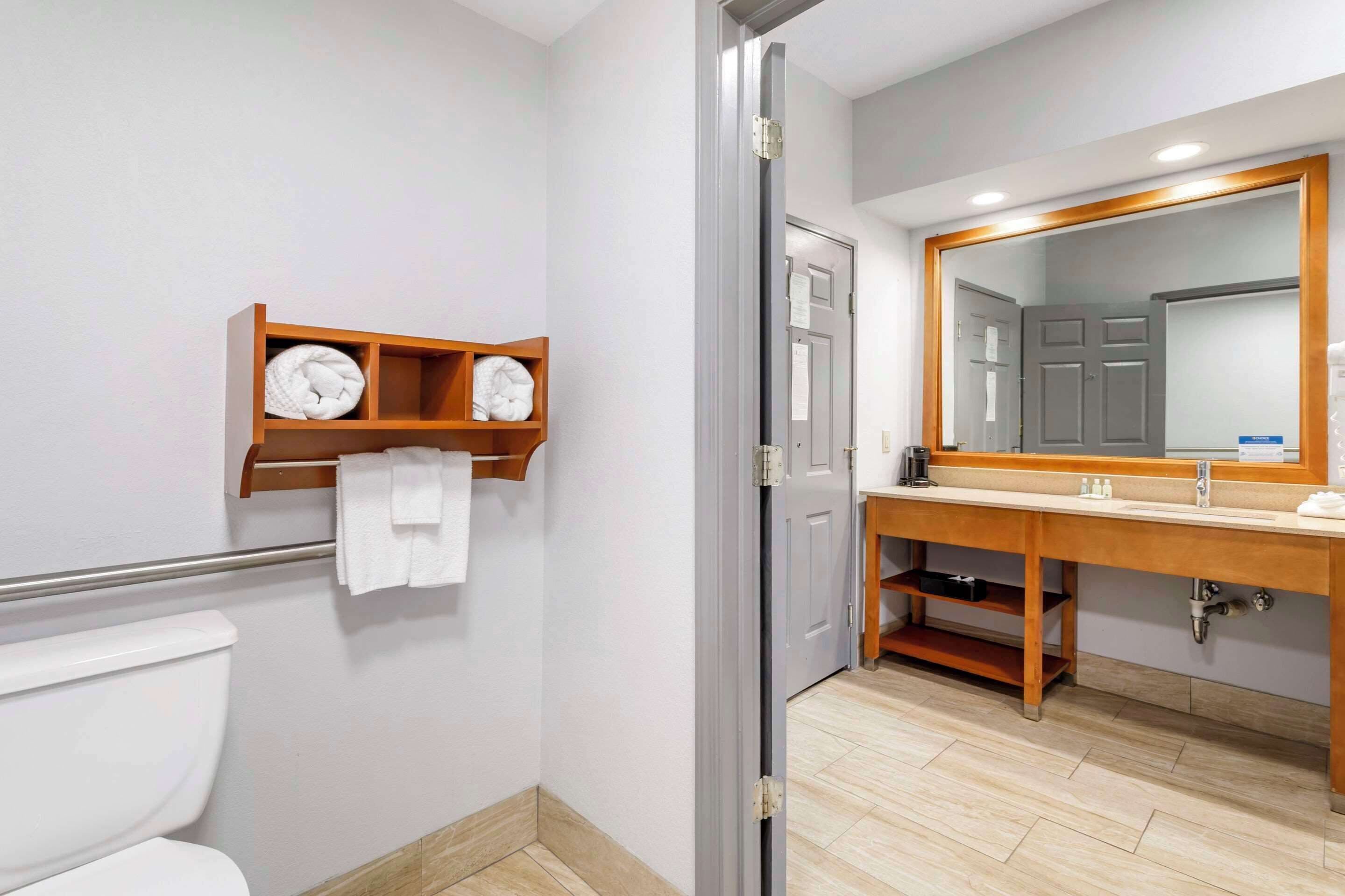 A bathroom with a toilet, a sink, a mirror, and a towel rack.