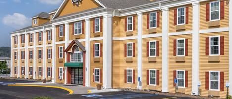 A multi-story hotel with a yellow facade, red shutters, and a green awning.