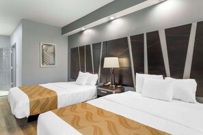 A hotel room with two beds, a nightstand, a lamp, and a framed picture on the wall.
