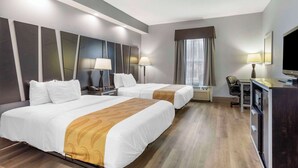 Ein Hotelzimmer mit zwei Betten, einem Schreibtisch mit Stuhl, einem Fernseher und einer Minibar.