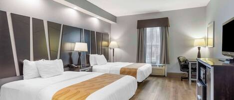 Habitación de hotel con dos camas, un escritorio con silla, televisor y minibar.