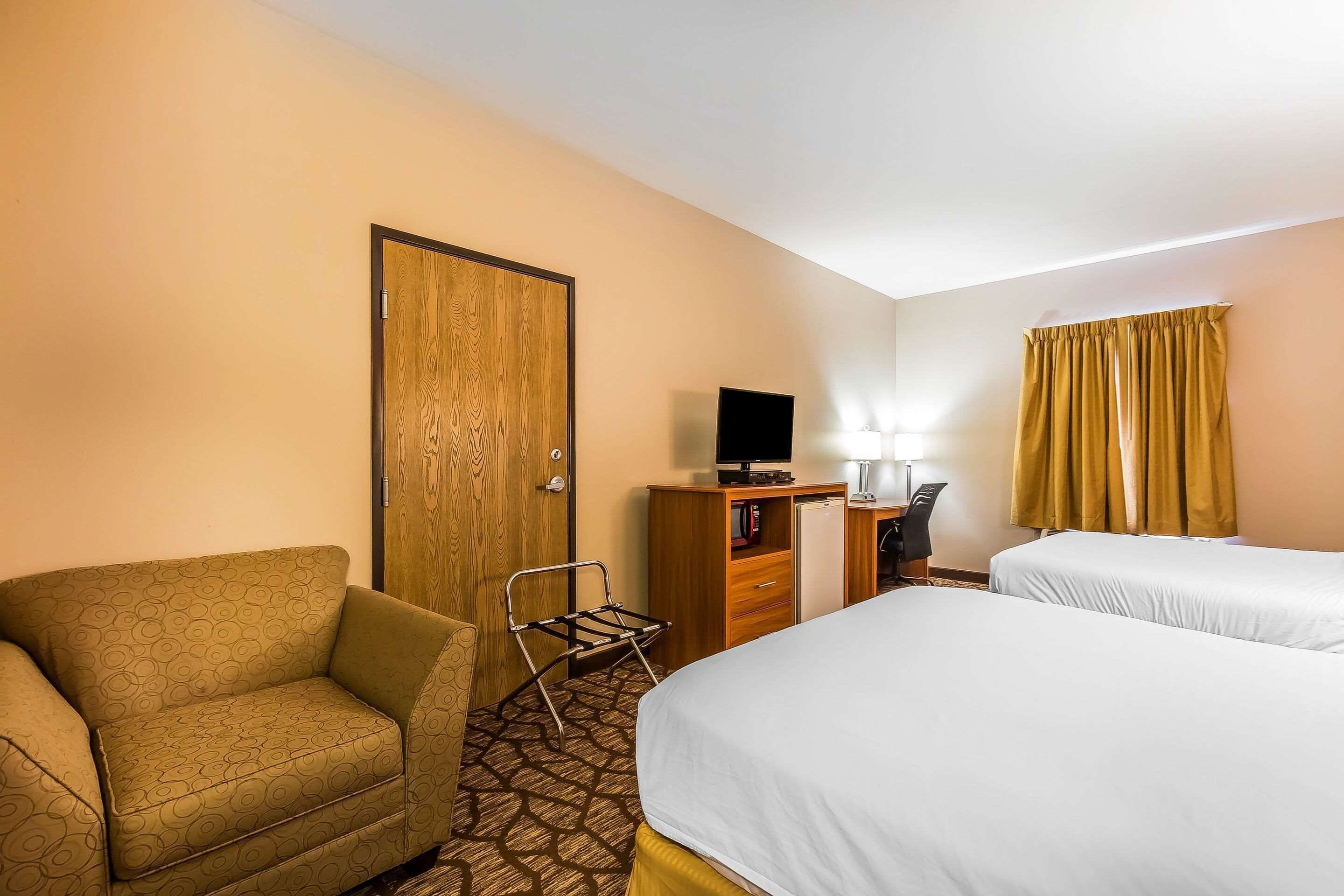 Habitación de hotel con sofá, cama, televisor, escritorio con computadora y armario.