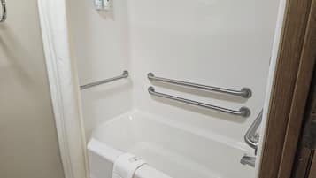 A white bathtub with grab bars and a towel rack.