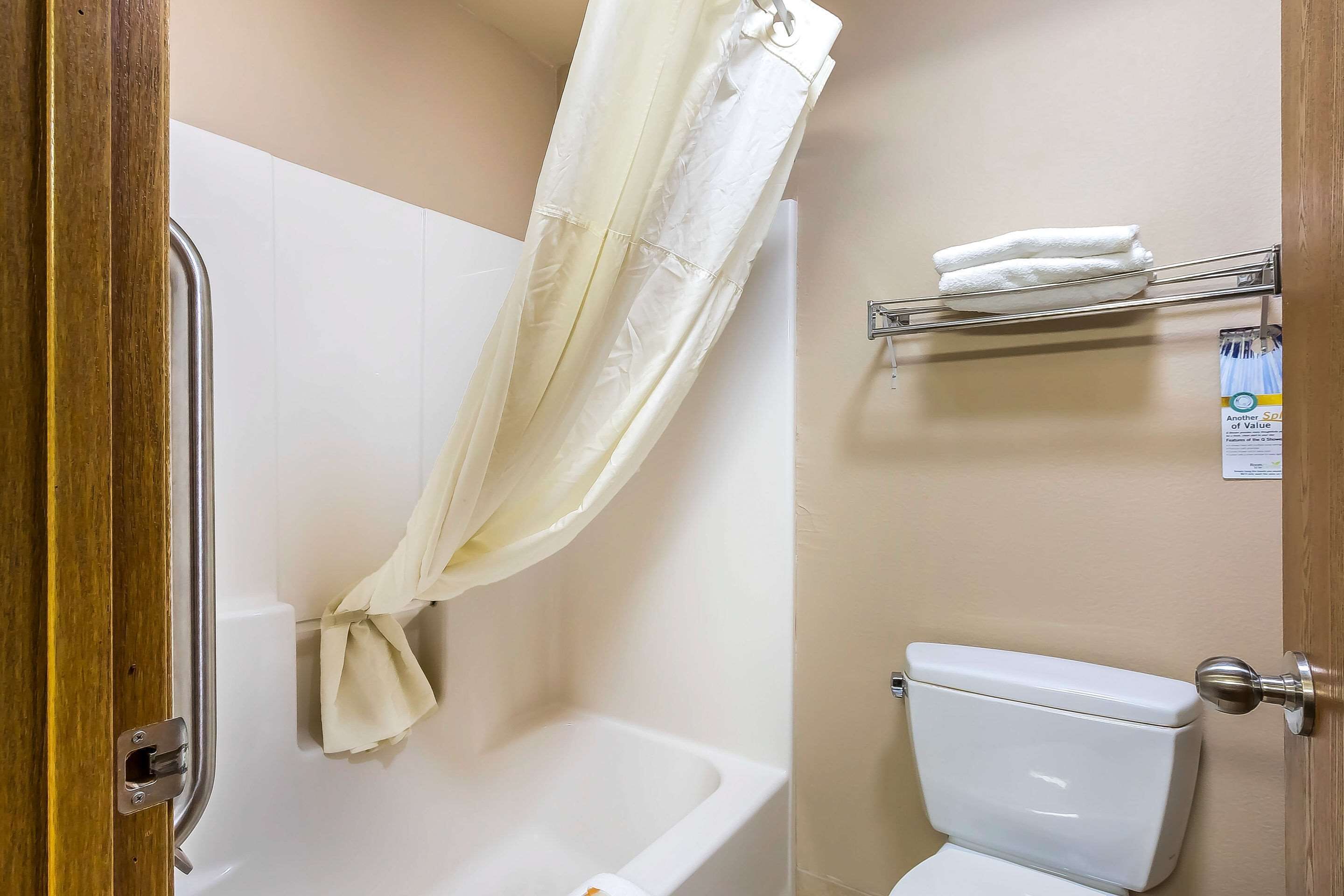 Ein Badezimmer mit Duschvorhang, Badewanne, Toilette und Handtuchhalter.