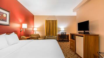 Una habitación de hotel con una cama grande, un escritorio con silla, televisión y minibar.