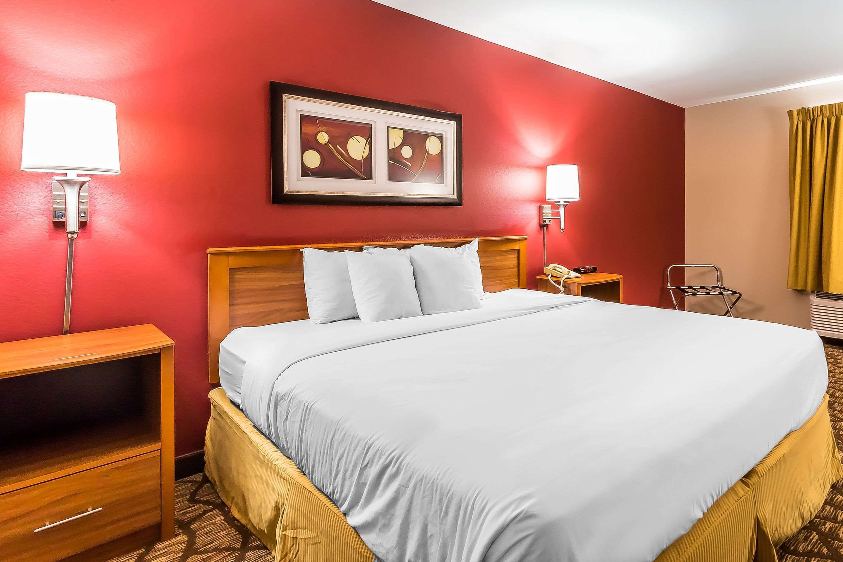 Habitación de hotel con una cama grande, dos mesitas de noche, una silla y un cuadro en la pared.