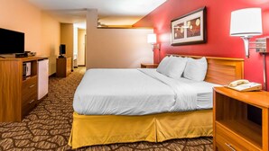 Habitación de hotel con cama, mesita de noche, lámpara y televisión.