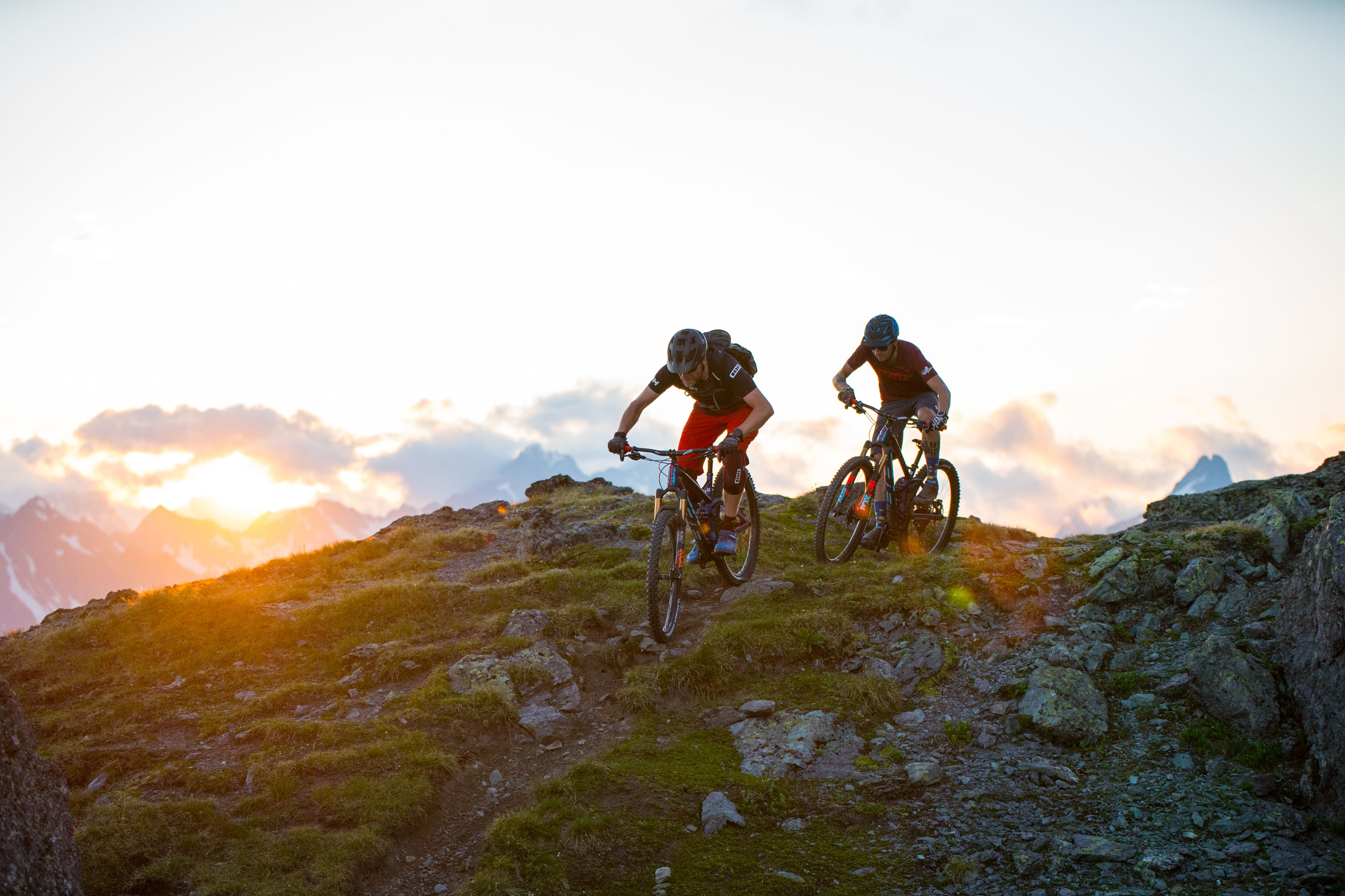 Deux vététistes sur un sentier rocailleux, avec une montagne en arrière-plan.