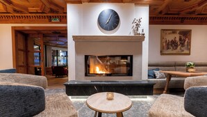 Un hall acogedor con chimenea, asientos cómodos y un reloj en la pared.