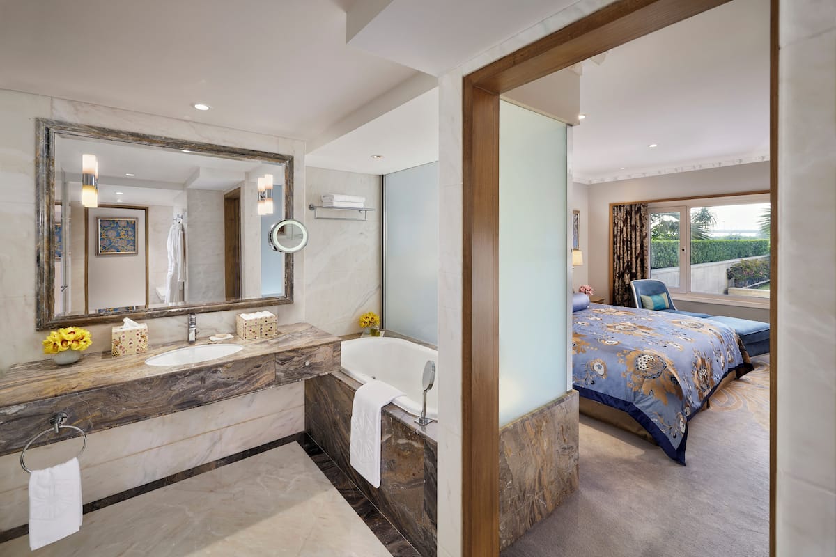 A modern bathroom with a marble sink, a bathtub, and a large mirror.