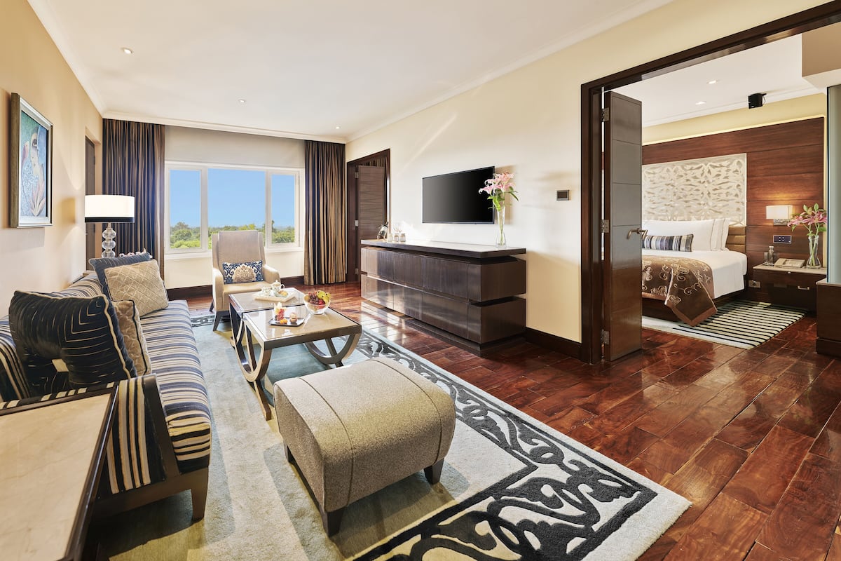 A spacious hotel room with a large bed, a sofa, a coffee table, and a TV.