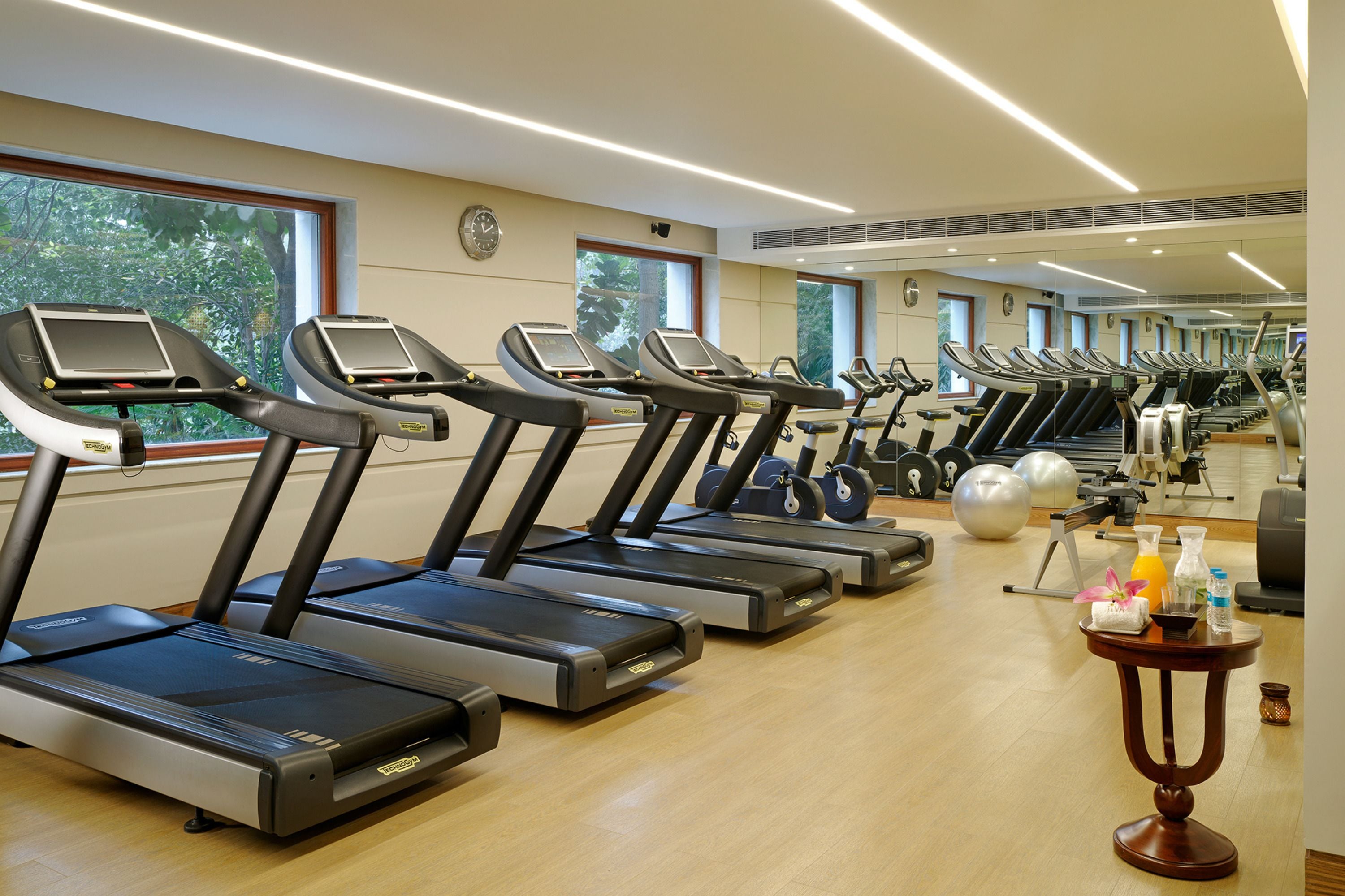A gym with multiple treadmills, exercise balls, and a small table with water bottles and a towel.