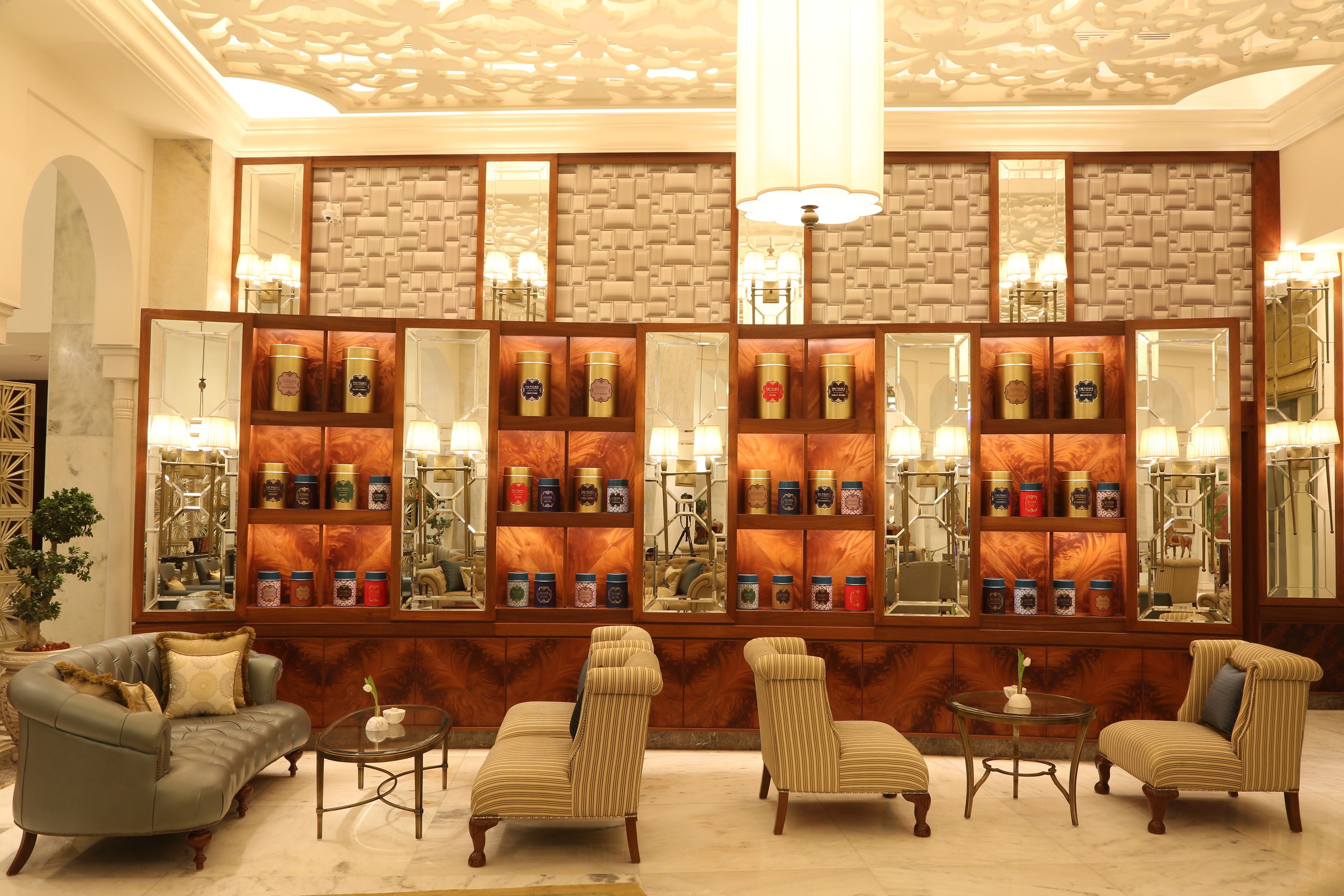 Een lobby met een centraal wand van spiegels, planken met decoratieve objecten en zithoekjes.