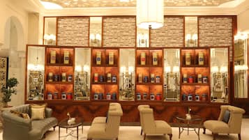 Een lobby met een centraal wand van spiegels, planken met decoratieve objecten en zithoekjes.