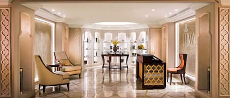 A spacious lobby with a geometric patterned floor, a central table with chairs, and decorative shelving with vases.